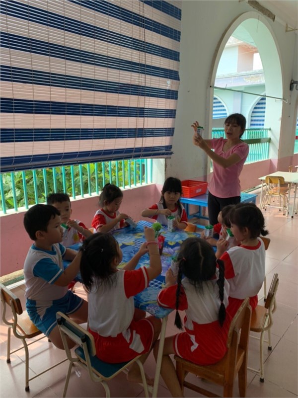 Cô hướng dẫn trẻ gấp vỏ hộp sữa.JPG
